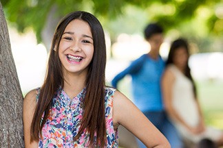 Brunette Teen with Braces Leaning Against Tree