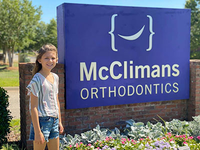 Child standing by McClimans Ortho sign