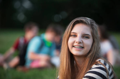 Girl with light brown hair smiling with braces